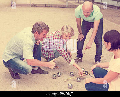 Allegro maschi e femmine giocando a bocce in th park nei giorni festivi Foto Stock