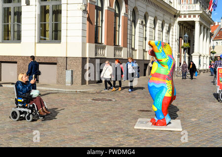 Una donna su una sedia a rotelle nella zona pedonale del centro della città di Riga, Lettonia Foto Stock