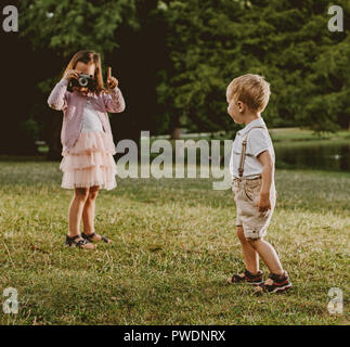 Carino, bambina prendendo un phto di suo fratello più giovane Foto Stock