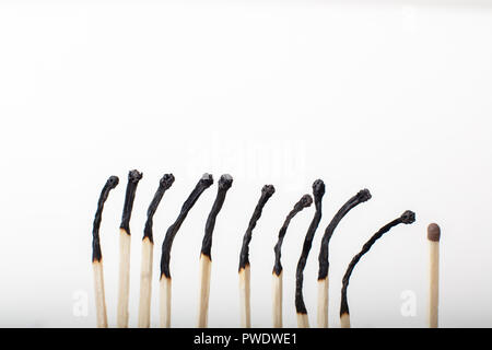 Fila di bruciato corrisponde con uno matchstick inutilizzati alla fine in un concetto di individualità, leadership, diversità ed essere unico su un bianco backgrou Foto Stock