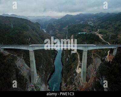 (181015) -- GUIYANG, Ott. 15, 2018 (Xinhua) -- In questa foto aerea adottate il 25 gennaio 2018, un treno che passa il Fiume Wujiang ponte in Zunyi, a sud-ovest della Cina di Guizhou. Nel sud-ovest della Cina di Guizhou, dove infinite colline carsiche dominano la terra, con i moderni mezzi di trasporto è reso possibile grazie a più di 20.000 ponti che attraversano sopra le valli. La provincia facilmente giustifica di per sé come un museo di ponti: tra il mondo di 100 ponti più alti, 46 sono situati nel Guizhou. Oltre quattro decenni dalla Cina di riforma e apertura, generazioni di costruttori di ponti hanno Foto Stock