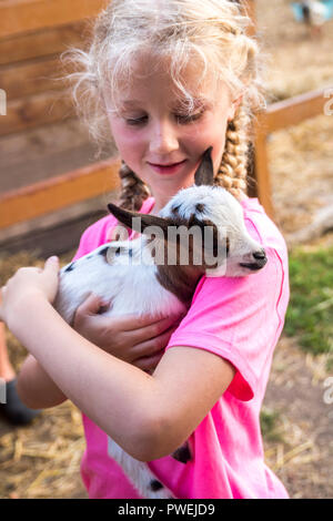 Primo piano di un bambino tenendo un baby capra, mostrando gentilezza amore delicato concetto, natura, baby animali da fattoria, baby animale, piccole cose, felicità Foto Stock