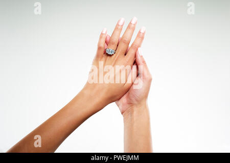 Modello femminile delle mani con platino oro bianco anello di fidanzamento con uno smeraldo diamante taglio baguette Foto Stock