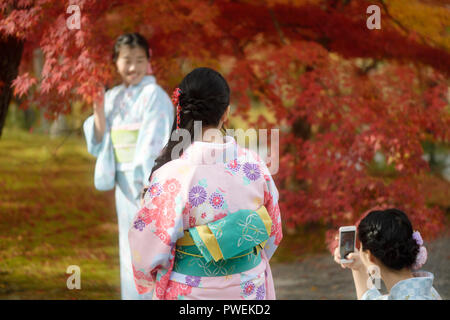 Ragazze giapponesi in colorate yukatas a scattare foto in un bellissimo paesaggio autunnale, Kyoto, Giappone 2017 Foto Stock