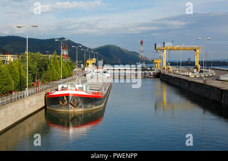 La Serbia, Romania, Carpazi Meridionali, serbo Carpazi, Banato montagne, cancelli in ferro, acqua del Danubio gap, crociera lungo il fiume Danubio, il cancello di ferro impianto di potenza 1, la Centrale Idroelettrica, Djerdap 1, Derdap 1, Hydro Power Plant, Danubio Power Plant, run-di-il-fiume Power Plant, serratura, freighter, paesaggio del fiume Danubio, paesaggio, la navigazione sul Danubio Foto Stock