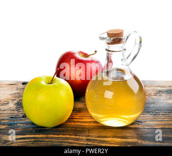 Apple di aceto di sidro in una bottiglia di vetro e mature mele fresche, sul tavolo di legno, su sfondo bianco Foto Stock