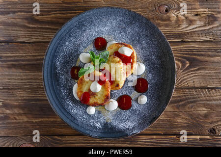 Vista superiore del formaggio frittelle servito con panna acida e confettura di fragole Foto Stock