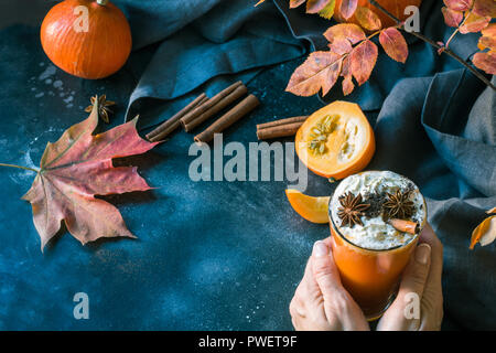 Succo di zucca con panna montata in mano femminile sul buio. Autunno autunno o inverno bevanda calda. Accogliente bevanda salutare. Foto Stock