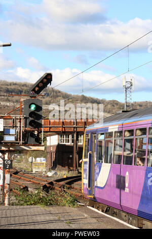 Pacer diesel multiple unit treno in partenza Carnforth stazione ferroviaria passando un segnale a colori alla fine della piattaforma 1 come si prende la linea verso Leeds. Foto Stock