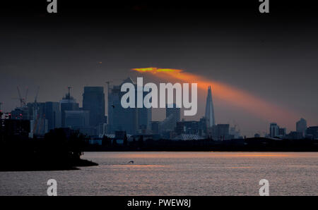 Un frammento di luce del sole risplende attraverso le nuvole sopra il grattacielo Shard e Canary Wharf al tramonto, Londra, Inghilterra. Foto Stock