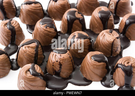 Pezzi di bomboni ricoperti di cioccolato fuso isolato su sfondo bianco Foto Stock