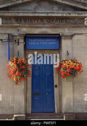 Un vecchio ufficio in Thornbury, Gloucestershire, UK è ora un pesce e patatine shop con un luminoso blu e porta due coloratissimi cesti floreali pendenti Foto Stock