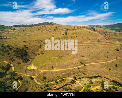 Strade sterrate e colline erbose in campagna australiana Foto Stock