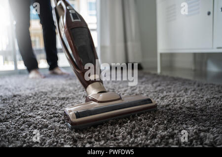 Close-up uomo utilizzando un aspirapolvere mentre la pulizia in camera Foto Stock
