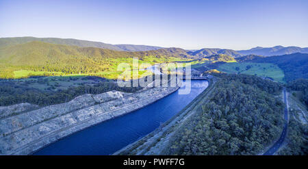 Panoramica aerea di canale d'acqua portando a Tumut Power Station e bellissime colline al tramonto. NSW, Australia Foto Stock