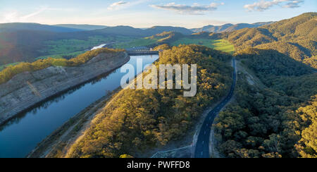 Tumut stazione di alimentazione 3 e la strada rurale tra le colline e gli alberi al tramonto. Talbingo, NSW, Australia Foto Stock