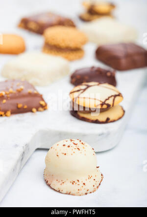 Il lusso di cioccolato belga e biscuit Cookie selezione sulla scheda di marmo e tavolo da cucina dello sfondo. Foto Stock