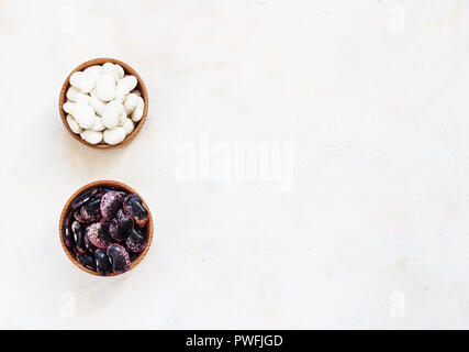 Diversi tipi di legumi - fagioli cannellini, nero e fagioli rossi, Lima e Fagioli Pinto aveva ordinato in ciotole di legno. Foto Stock