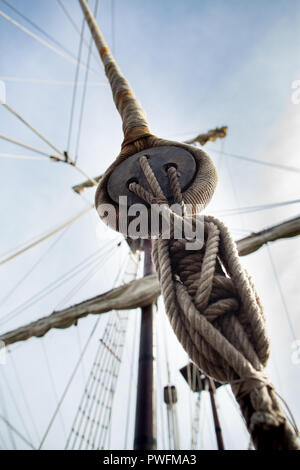 Vista dal basso portano la linea attraverso uno dei blocchi di sorella e torna fuori attraverso il blocco al palo punta. Corde sulla vecchia nave arrugginito Closeup. Foto Stock