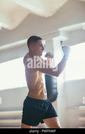 Sportivo muay thai boxer combattimenti in palestra. Uomo muscolare funziona in posizione migliore per combattere. Sport concept Foto Stock