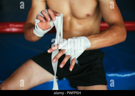 Boxer uomo si avvolge le mani con il pugilato si avvolge. Concetto di inscatolamento Foto Stock