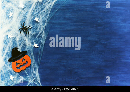 Sfondo di Halloween. Ragnatela, ragni e jack sorridente decorazioni - i simboli di Halloween sul blu scuro dello sfondo in legno Foto Stock