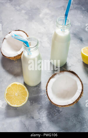 Noce di cocco latte vegano coctail in bottiglia su sfondo di calcestruzzo. Foto Stock