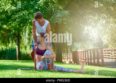 A piena lunghezza shot della giovane donna a praticare yoga con il suo maschio istruttore. Foto Stock