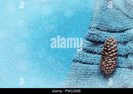 Inverno sfondo. Cono di abete su grigio felpa lavorata a maglia con nevicate invernali. Inverno ancora in vita, libera lo spazio per testo Foto Stock