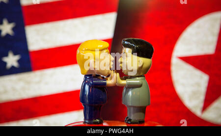 Presidente Trump e Kim Jong onu bobble testine di riproduzione di Patty la torta nella parte anteriore della bandiera americana e nord Bandiera coreana Foto Stock