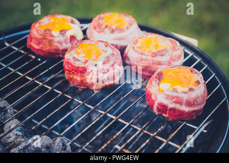 Rendendo fatta in casa birra può Bacon gli hamburger sul grill barbecue. La preparazione di polpette ripiene, avvolto in pancetta e grigliare sul calore indiretta nella natura a bac Foto Stock