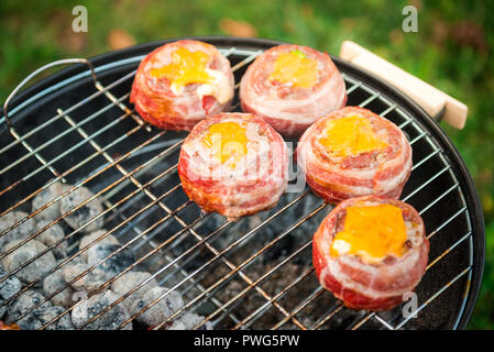 Rendendo fatta in casa birra può Bacon gli hamburger sul grill barbecue. La preparazione di polpette ripiene, avvolto in pancetta e grigliare sul calore indiretta nella natura a bac Foto Stock