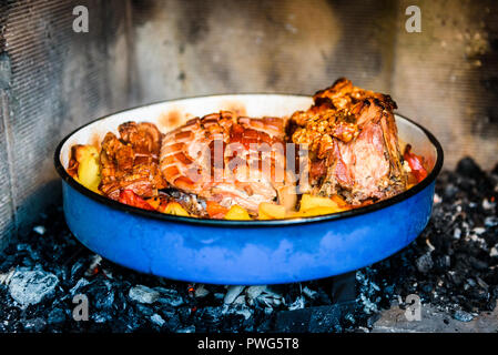 La preparazione e la cottura arrosto di maiale nella tradizionale pentola di metallo Peka. La carne e le verdure nel tradizionale dei Balcani, croato, greco pasto mediterraneo Peka in Foto Stock