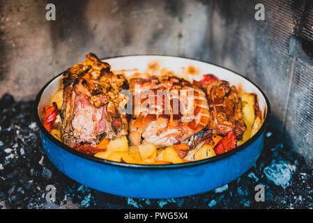 La preparazione e la cottura arrosto di maiale nella tradizionale pentola di metallo Peka. La carne e le verdure nel tradizionale dei Balcani, croato, greco pasto mediterraneo Peka in Foto Stock
