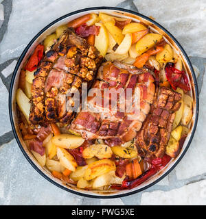 La preparazione e la cottura arrosto di maiale nella tradizionale pentola di metallo Peka. La carne e le verdure nel tradizionale dei Balcani, croato, greco pasto mediterraneo Peka in Foto Stock
