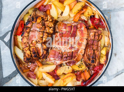 La preparazione e la cottura arrosto di maiale nella tradizionale pentola di metallo Peka. La carne e le verdure nel tradizionale dei Balcani, croato, greco pasto mediterraneo Peka in Foto Stock