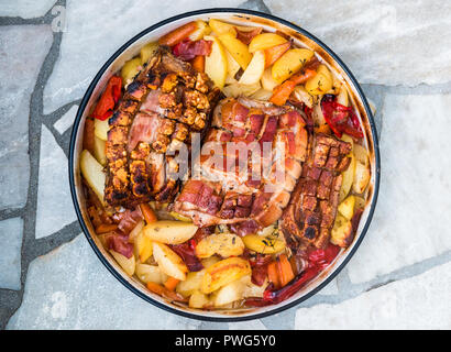 La preparazione e la cottura arrosto di maiale nella tradizionale pentola di metallo Peka. La carne e le verdure nel tradizionale dei Balcani, croato, greco pasto mediterraneo Peka in Foto Stock