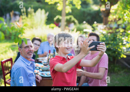Durante un barbecue un giovane ragazzo fa un selfie con tutta la famiglia Foto Stock
