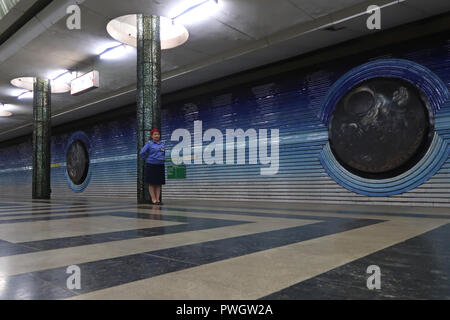 Un personale di sicurezza guardia accanto a pitture murali del periodo sovietico dedicato alla sovietica cosmonauti Kosmonavtlar alla stazione della metropolitana di Tashkent Metro in Uzbekistan. La metropolitana di Tashkent costruito nella ex URSS è solo uno dei due sistemi di metropolitana attualmente operativo in Asia centrale e le sue stazioni sono tra i più ornato nel mondo. Foto Stock