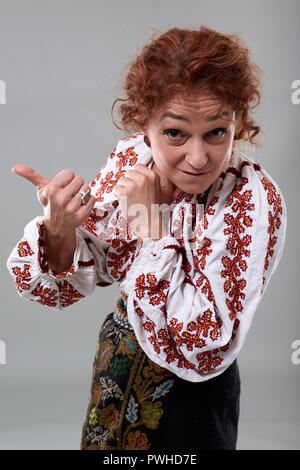 Matura donna rumena in costume tradizionale su sfondo grigio Foto Stock