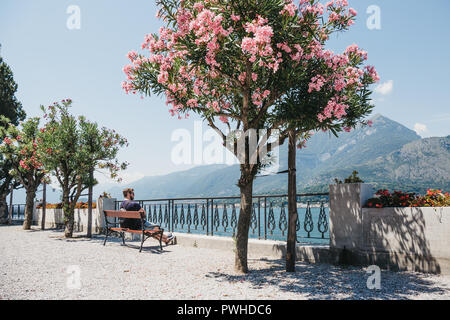 Bellagio, Italia - Luglio 06, 2017: uomo relax su una panchina di Bellagio, affacciato sul lago di Como. Bellagio è spesso indicata come la "Perla del Lago". Foto Stock