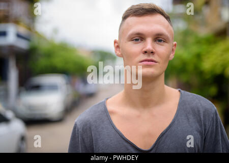 Giovane uomo che indossa maglietta grigio nelle strade all'aperto Foto Stock