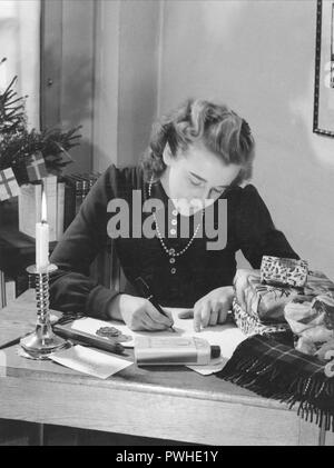 Natale nel 1940s. Una donna è un involucro di regali di Natale. La Svezia 1940s Foto Stock