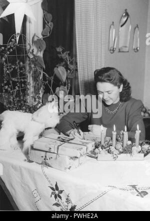 Natale nel 1940s. Una donna è un involucro di regali di Natale. La Svezia 1940s Foto Stock