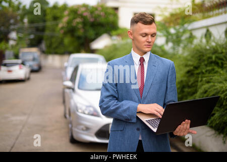 Giovane uomo d affari con computer portatile nelle strade all'aperto Foto Stock