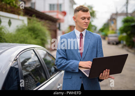 Giovane uomo d affari con computer portatile nelle strade all'aperto Foto Stock