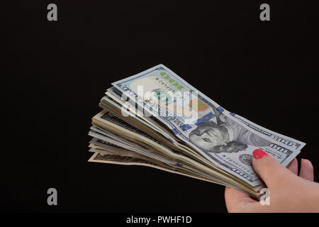 Giovani mani femminili contare le fatture del dollaro su sfondo nero, primo piano Foto Stock