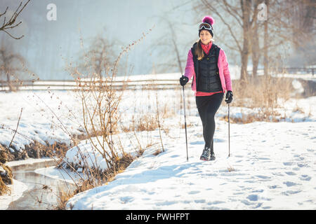 Montare donna Nordic walking nel paesaggio invernale Foto Stock