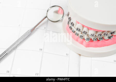 Modello di denti con filo metallico bretelle dentale su un calendario. Checkup periodiche sono essenziali per la salute orale Foto Stock