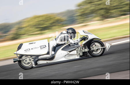 Graham Sykes sulla sua moto a razzo a vapore "Force of Nature" viene trainato dietro un furgone, mentre prova la sua moto in preparazione al suo tentativo di record mondiale di velocità terrestre per un veicolo a vapore, durante l'evento Straightliners a velocità massima e ruote all'Elvington Airfield nello Yorkshire. Foto Stock